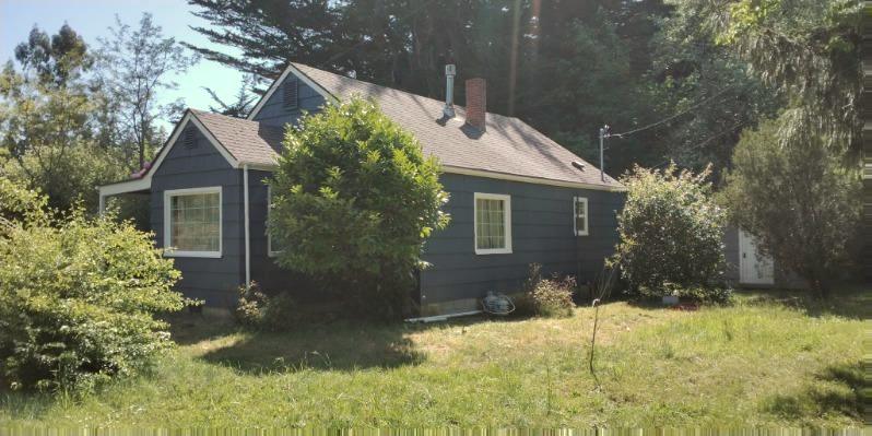 The same cottage wall after painting, deep navy with white window trim.